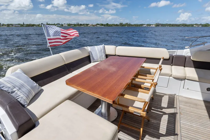 Knot On Call Yacht Photos Pics Azimut 55S 2015 yacht deck with seating, table, and American flag on a sunny day.