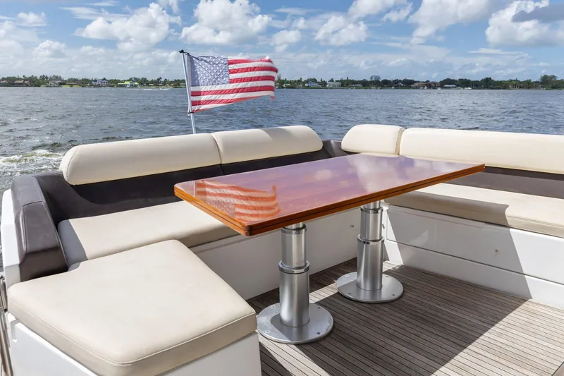 Knot On Call Yacht Photos Pics Azimut 55S 2015 yacht deck with seating, table, and American flag on a sunny day.