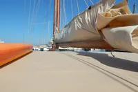Vintage 1944 Custom Schooner 22 m with sails furled, docked under clear blue sky.