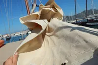 Sail of a 1944 Custom Schooner 22 m, docked in a sunny marina.