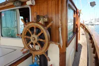 Wooden helm of a 1944 Custom Schooner 22 m, docked at a marina.