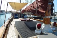 Custom Schooner 22 m, 1944, with wooden deck and sails, docked in a marina.
