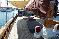 1944 Custom Schooner 22 m with wooden deck, docked at marina, featuring sails and sunshade.