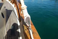 Wooden deck of a 1944 Custom Schooner 22 m, featuring rigging and clear blue water.