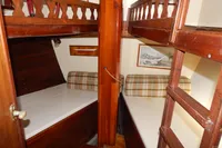 Wooden interior cabin of 1944 Custom Schooner 22 m with bunk beds and plaid cushions.