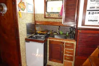 Vintage 1944 Custom Schooner kitchen with stove, sink, and wooden cabinetry.