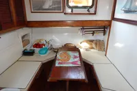 Cozy dining area in a 1944 Custom Schooner, featuring a wooden table and cushioned seating.