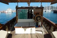Vintage 1944 Custom Schooner 22 m with wooden helm, docked in a marina.
