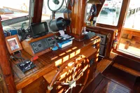 Wooden helm of a 1944 Custom Schooner 22 m with navigation equipment and nautical decor.
