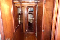 Wood-paneled hallway inside a 1944 Custom Schooner 22 m, featuring doors and mirrors.