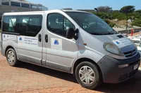 Silver van with business signage parked on a sunny day near a marina.