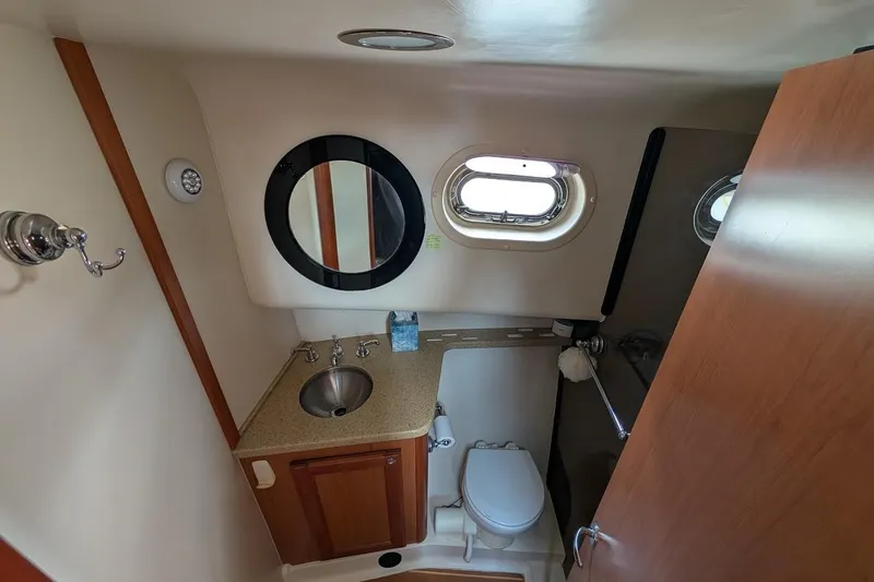 Lulu Jack Yacht Photos Pics 2008 Mainship 38 yacht bathroom with sink, toilet, mirror, and porthole window.