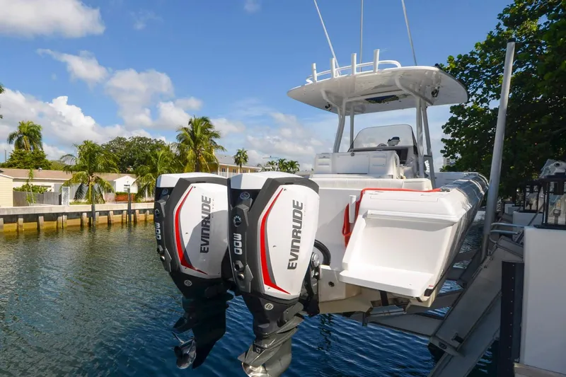 Quid Pro Quo Yacht Photos Pics 2013 Intrepid 300 Center Console boat with dual Evinrude engines docked by palm trees.