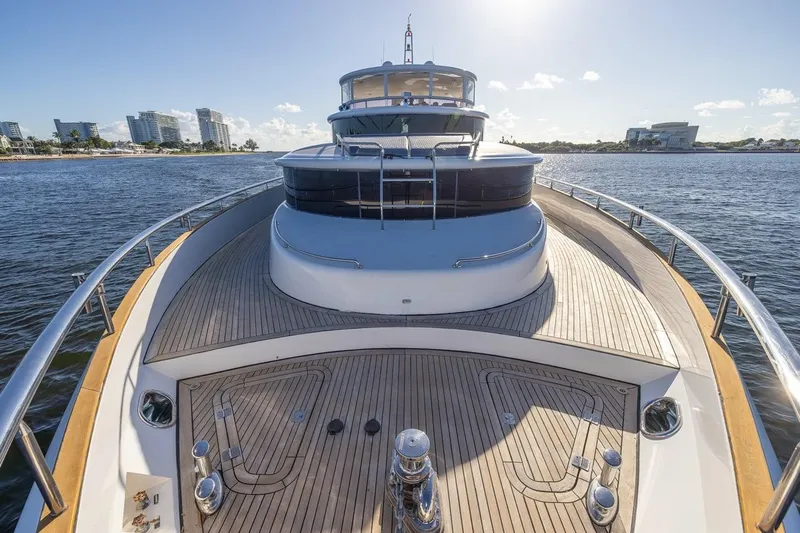 Kaya Yacht Photos Pics Luxurious 2003 Johnson 87' Motor Yacht on serene waters, cityscape in background.