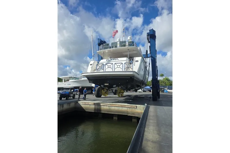 Kaya Yacht Photos Pics Johnson 87' Motor Yacht 2003 being lifted at a marina under a cloudy sky.