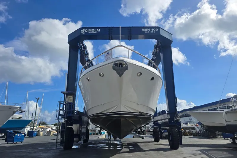 Kaya Yacht Photos Pics Johnson 87' Motor Yacht 2003 on a lift at a marina under a blue sky.