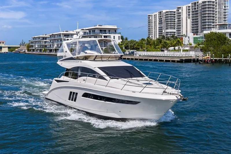 Ern'd It Yacht Photos Pics 2017 Sea Ray Fly 510 yacht cruising near modern waterfront buildings.