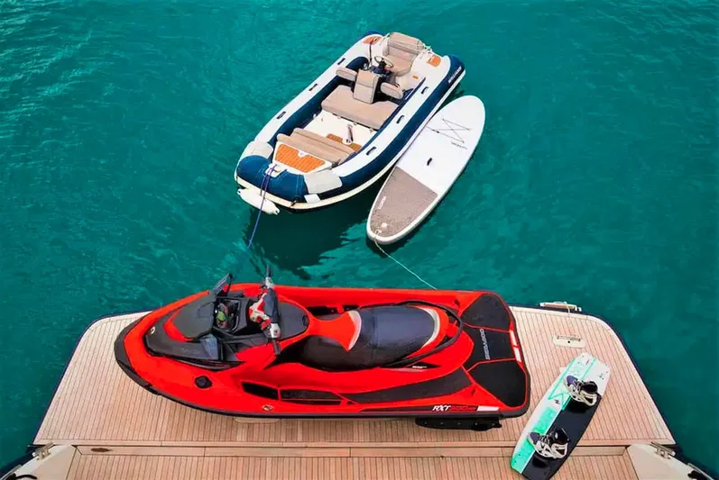  Yacht Photos Pics Luxury yacht deck with jet ski, inflatable boat, and paddleboard on turquoise water.