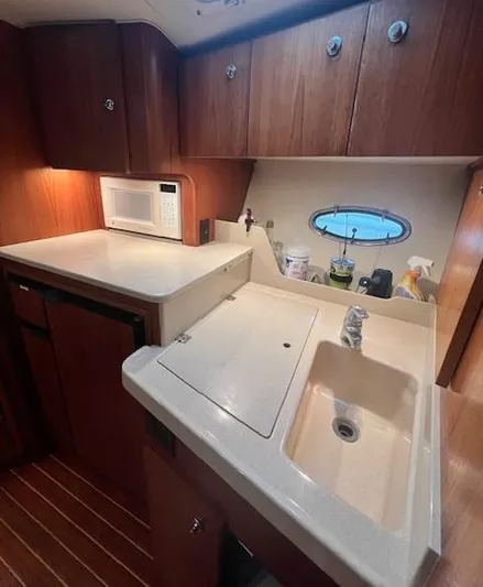 First Light II Yacht Photos Pics 1998 Tiara Yachts 3500 Open kitchen with sink, microwave, and wooden cabinets.