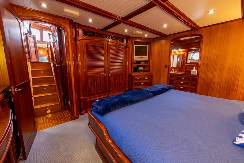 Liberty Yacht Photos Pics Luxurious 2004 Lyman-Morse motoryacht bedroom with wooden interior and blue bedding.