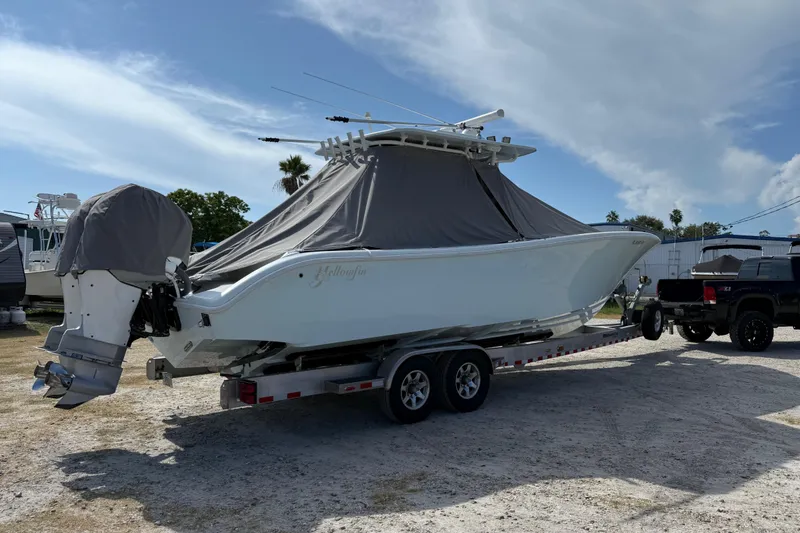  Yacht Photos Pics 2018 Yellowfin 32 Offshore boat on trailer, covered, with truck nearby under blue sky.
