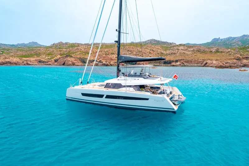 Semper Fidelis Yacht Photos Pics 2022 Fountaine Pajot Alegria 67 catamaran sailing in clear turquoise waters.