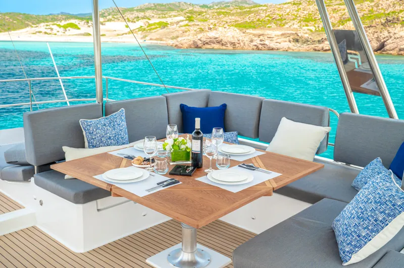 Semper Fidelis Yacht Photos Pics Luxury dining setup on 2022 Fountaine Pajot Alegria 67 yacht, overlooking turquoise waters.