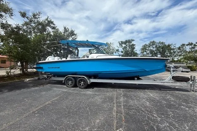  Yacht Photos Pics 2025 Axopar 29 Sun Top boat on trailer, vibrant blue hull, parked outdoors.