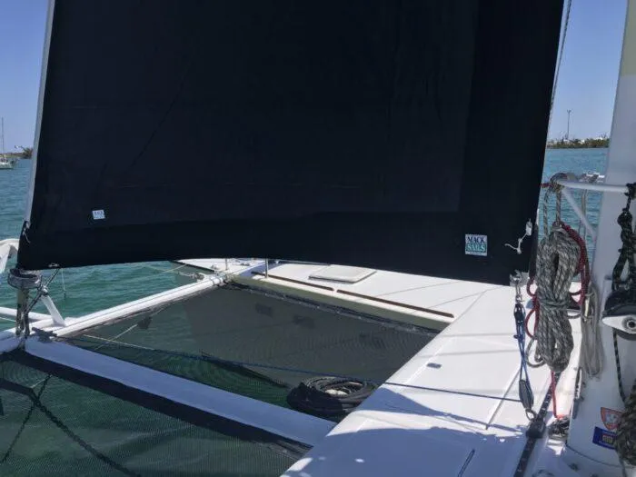 Vitesse Yacht Photos Pics Lagoon 55 catamaran (1989) with black sail, docked on calm waters.