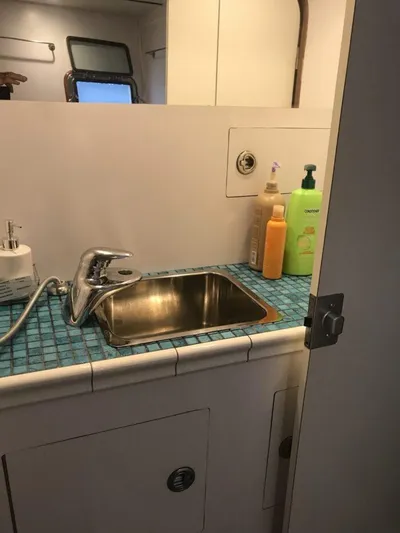 Vitesse Yacht Photos Pics 1989 Lagoon 55 yacht bathroom sink with toiletries on blue-tiled countertop.