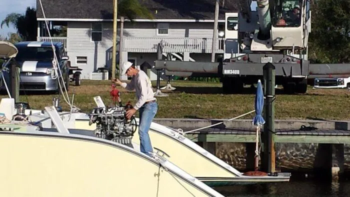 Vitesse Yacht Photos Pics Man working on a 1989 Lagoon 55 yacht engine at a dock.