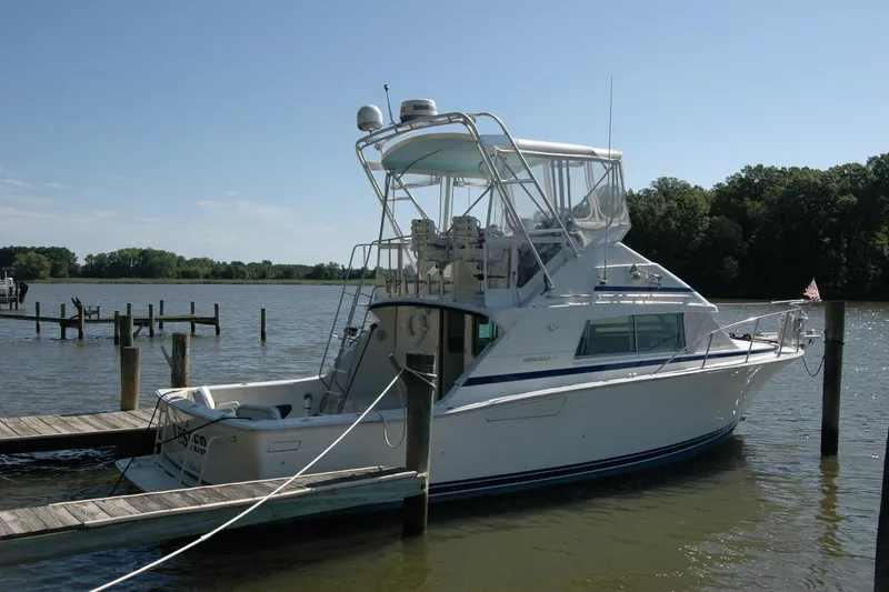 Vesper Yacht Photos Pics 1987 Bertram 33 Sport Fisherman docked on a calm lake under clear skies.