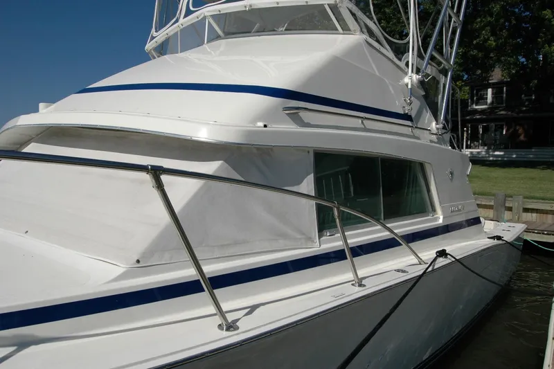 Vesper Yacht Photos Pics 1987 Bertram 33 Sport Fisherman boat docked, featuring sleek white and blue design.