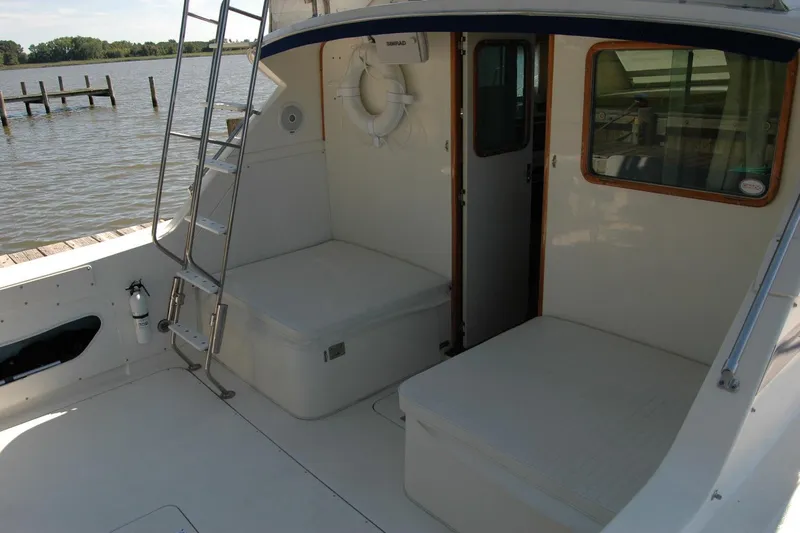 Vesper Yacht Photos Pics 1987 Bertram 33 Sport Fisherman boat interior with seating and ladder by the water.