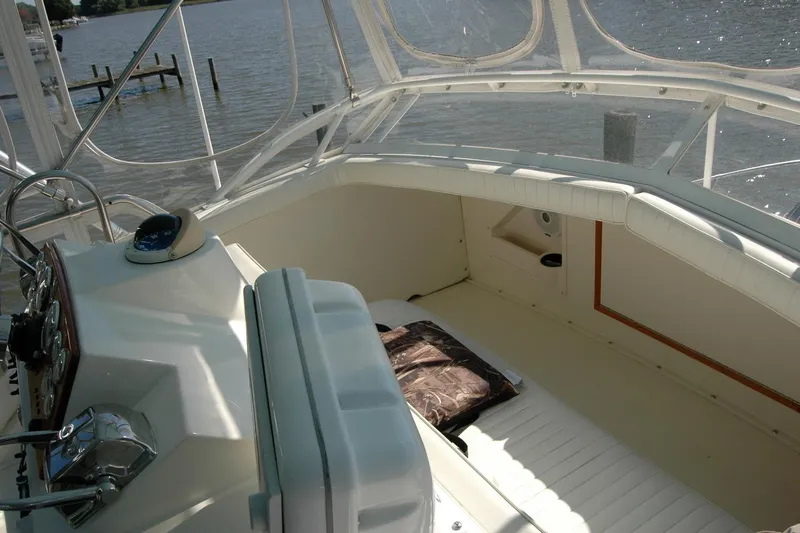 Vesper Yacht Photos Pics 1987 Bertram 33 Sport Fisherman boat interior with helm and seating area, docked by the water.