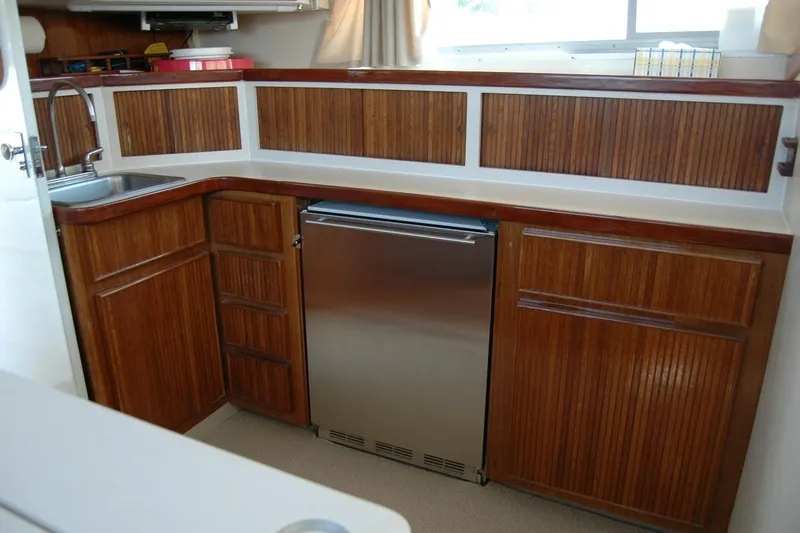 Vesper Yacht Photos Pics 1987 Bertram 33 Sport Fisherman galley with wood cabinetry and stainless steel fridge.