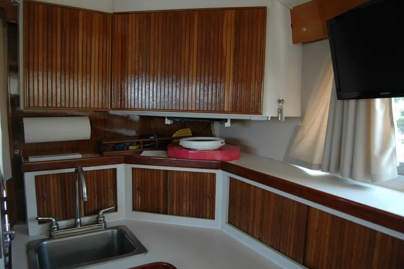 Vesper Yacht Photos Pics 1987 Bertram 33 Sport Fisherman interior kitchen with wooden cabinets and modern amenities.