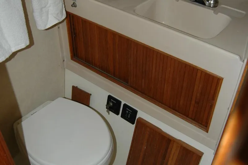 Vesper Yacht Photos Pics 1987 Bertram 33 Sport Fisherman bathroom with wooden cabinetry and compact sink.