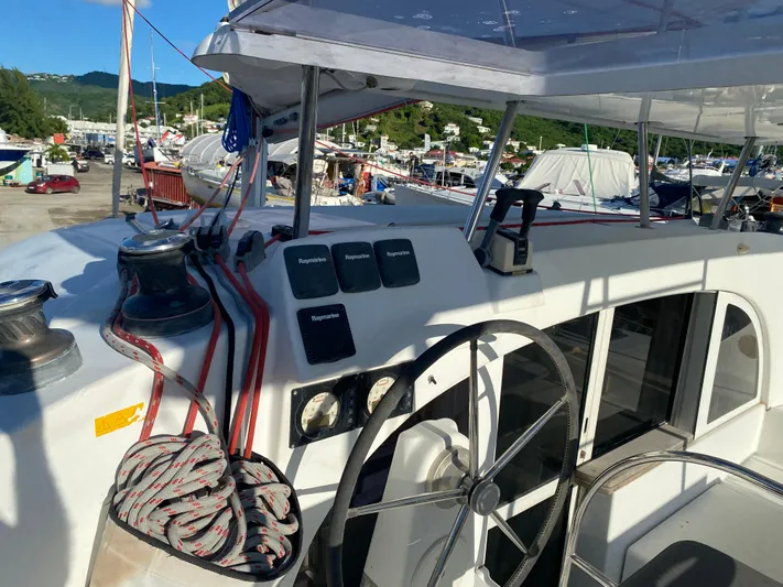 Eugenite Yacht Photos Pics Lagoon 380 catamaran cockpit with steering wheel and control panels, docked in a marina.