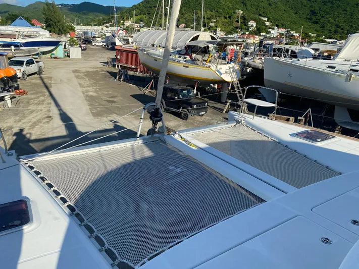 Eugenite Yacht Photos Pics Lagoon 380 catamaran on land, surrounded by boats, with green hills in the background.