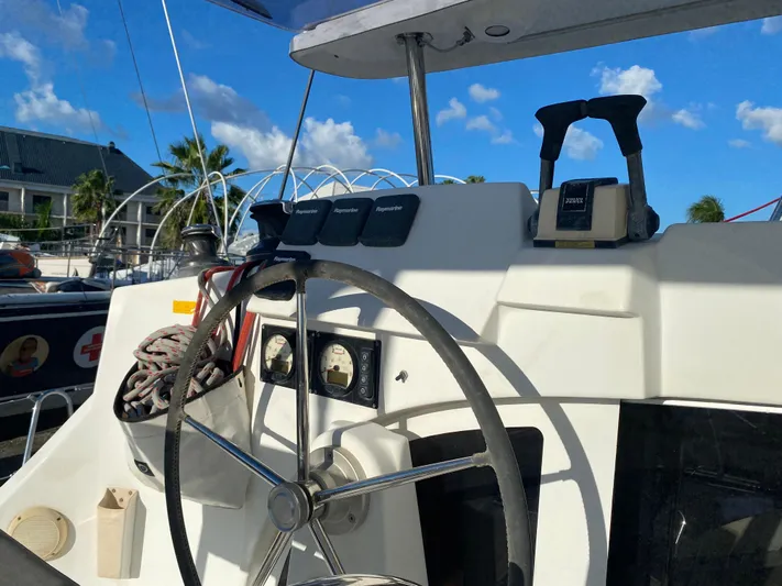 Eugenite Yacht Photos Pics Steering wheel of a 2013 Lagoon 380 catamaran under a clear blue sky.