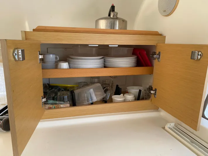 Eugenite Yacht Photos Pics Open wooden cabinet with dishes and cookware on a Lagoon 380, 2013 model.
