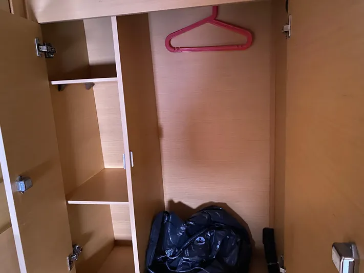 Eugenite Yacht Photos Pics Empty wooden closet with shelves, red hanger, and a black bag inside a 2013 Lagoon 380.