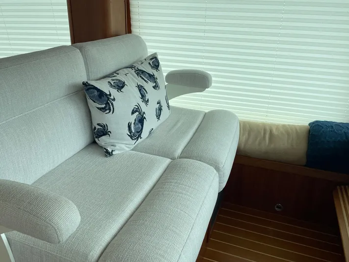 Last Resort Yacht Photos Pics Interior of 2021 Sabre 58 Salon Express with plush seating and crab-patterned pillow.