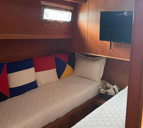Last Resort Yacht Photos Pics Cozy cabin interior of 2021 Sabre 58 Salon Express with colorful pillows and wall-mounted TV.