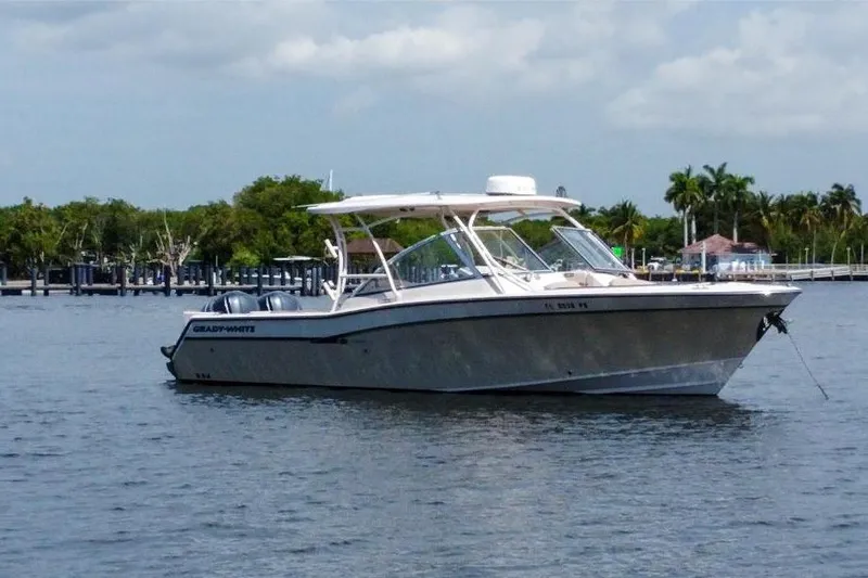  Yacht Photos Pics 2014 Grady-White Freedom 307 boat anchored on calm water with lush greenery background.