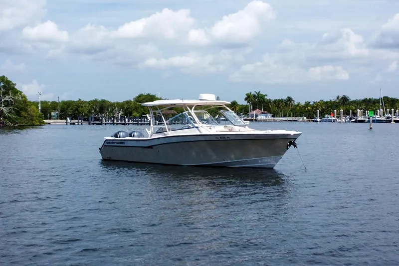  Yacht Photos Pics 2014 Grady-White Freedom 307 boat anchored on calm water, with marina and trees in background.