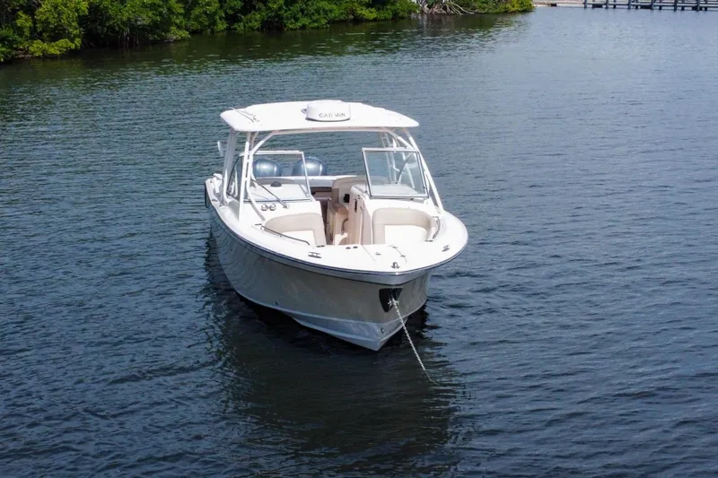  Yacht Photos Pics 2014 Grady-White Freedom 307 boat on calm water, surrounded by lush greenery.