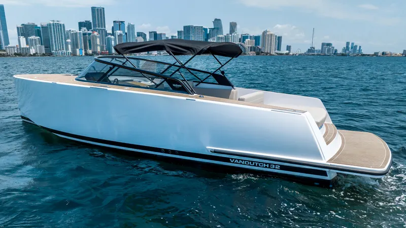  Yacht Photos Pics 2023 VanDutch 32 yacht cruising on blue water with city skyline in the background.