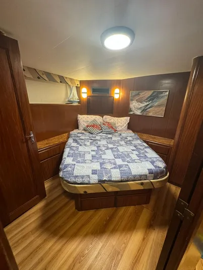  Yacht Photos Pics Cozy bedroom in 1990 Hatteras 45 Convertible yacht with wood paneling and quilted bedding.
